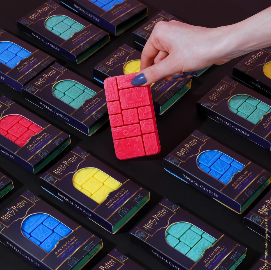Harry Potter&trade; wax melt collection featuring all four Hogwarts&trade; house bars, with a hand holding the Gryffindor&trade; inspired wax melt in our signature themed packaging.