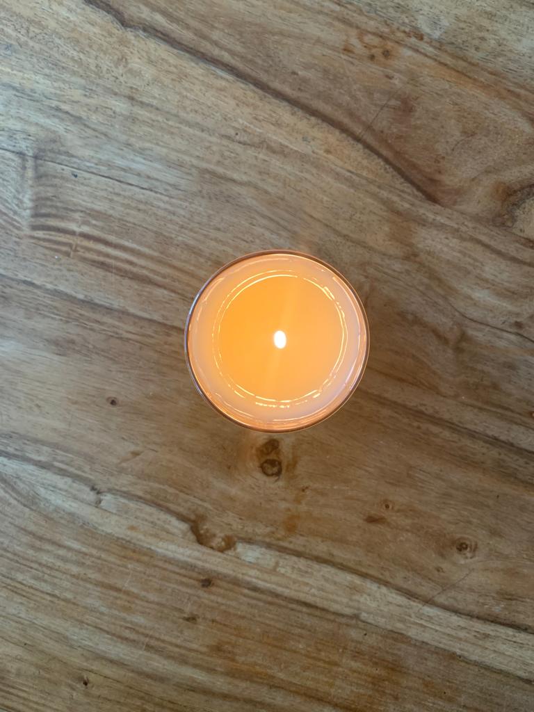 Lit Purscents candle on wooden surface