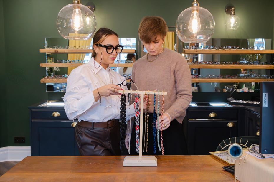 An optician helping a customer choose a glasses chain during her frame styling dispensing process